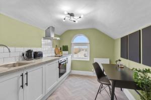 Rock FerryBirkenhead Aparthotel的厨房配有白色橱柜、桌子和窗户。