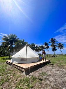 ZapotalGlamping La Isla Bonita (Isla Portete, Ecuador)的站在田野上白色帐篷旁边的男人