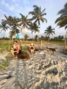 ZapotalGlamping La Isla Bonita (Isla Portete, Ecuador)的棕榈树海滩上的两个人和一只狗