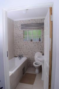 OtseKanana Villas的带浴缸、卫生间和盥洗盆的浴室