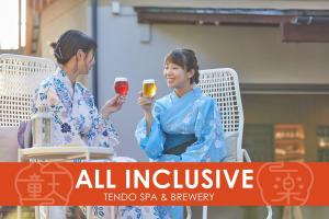 天童市Ichiraku tendo spa & brewery的两个坐在椅子上的女人拿着酒杯