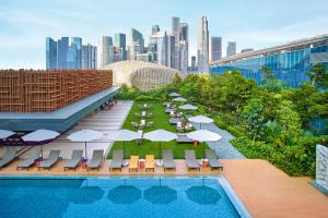 新加坡PARKROYAL COLLECTION Marina Bay, Singapore的一个带椅子和遮阳伞的游泳池,并享有城市天际线