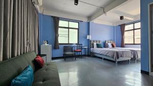 曼谷HOUSEMODE - BAANYAI @ Wongwian Yai的卧室拥有蓝色的墙壁,配有一张床和一张沙发