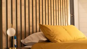 塞昆达Leipoldt Self-Catering Apartment的一张带黄色枕头的床和木制床头板
