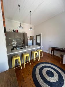 HardenMURRUMBURRAH ARTHOUSE APARTMENTS的厨房配有3张黄色凳子和1个柜台