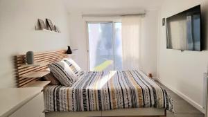 Gignac-la-NertheVilla Miami-4 chambres-Familiale-Calme-Soleil-Paisible的一间卧室设有一张床、一台电视和一个窗口。