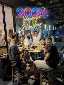 班敦孟Youyen Hostel的一群坐在桌子旁的人,带着快乐的新年标志