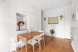 KillaraSerene Killara Guesthouse的一间带木桌和白色椅子的用餐室