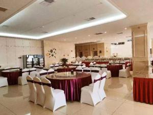华阴华山欣源国际酒店的一个带桌子和白色椅子的大型宴会厅