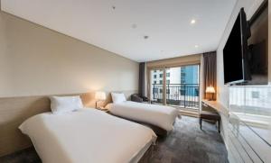 西归浦市济州岛城山贝斯特酒店的酒店客房设有两张床和一台平面电视。
