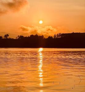 桑卡武里พาราไดซ์รีสอร์ต สังขละบุรี Paradise Resort at Sangkhlaburi的日落在水体上,日落在太阳下