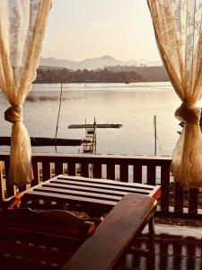 桑卡武里พาราไดซ์รีสอร์ต สังขละบุรี Paradise Resort at Sangkhlaburi的湖景门廊设有长凳