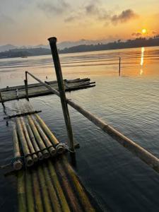 桑卡武里พาราไดซ์รีสอร์ต สังขละบุรี Paradise Resort at Sangkhlaburi的水面上的木头码头,背景是日落