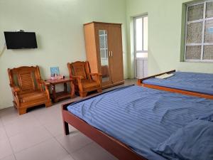 NHÀ NGHỈ THÀNH MINH的一间卧室配有一张床、两把椅子和电视