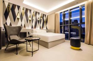 首尔Hotel The Designers Premier Kondae的配有一张床和一把椅子的酒店客房