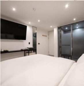 首尔Baron De Hotel的卧室配有一张白色大床和一台平面电视。