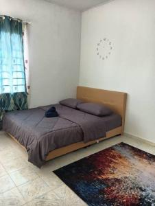 马六甲Homestay HNH Melaka (Corner Lot)的卧室配有一张床,卧室墙上挂着时钟