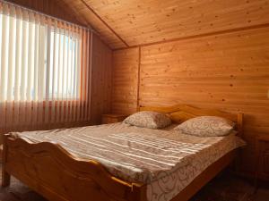 亚布卢尼齐亚Котедж Краєвид的木制客房内的一间卧室,配有一张床