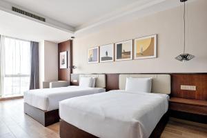 重庆重庆MontClassic精选酒店的配有白色床单的酒店客房内的两张床