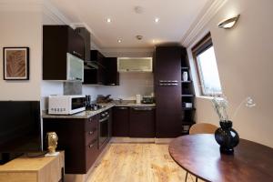 伦敦The London Cradle - Spacious 1BDR Flat的厨房配有黑色橱柜和木桌