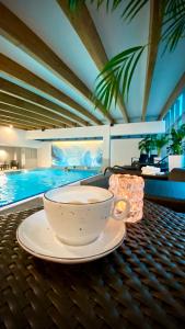 波兹南Andersia Hotel & Spa Poznan, a member of Radisson Individuals的坐在游泳池畔的桌子上喝杯咖啡