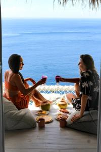 珀尼达岛Tropical Glamping Nusa Penida Diamond Beach - Cliff Side Edge的两个女人坐在桌子旁,吃喝
