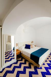 伊斯基亚大拉斐尔酒店 的卧室配有床,铺有蓝色和白色的地板