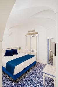 伊斯基亚大拉斐尔酒店 的卧室配有蓝色和白色的床和镜子