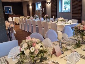 温德哈根风之4号餐厅酒店的一套桌子,上面摆放着白色的椅子和鲜花