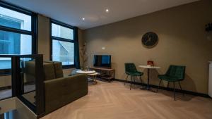 海牙Downtown Suite的客厅配有绿色椅子和墙上的时钟