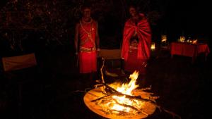 马赛马拉Soroi Mara Bush Camp的两个女人站在黑暗中火边