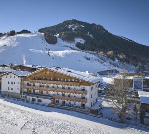 萨尔巴赫哈勃特斯诺夫酒店的山前雪中建筑物