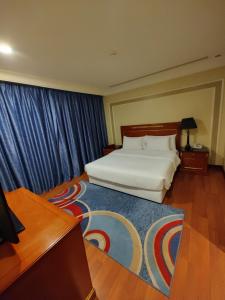 阿可贺巴فندق كارم الخبر - Karim Hotel Khobar的卧室配有白色的床和蓝色窗帘