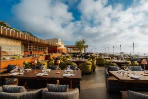 阿纳卡普里Jumeirah Capri Palace的海滩上的餐厅,配有桌椅