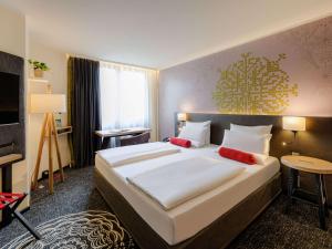 慕尼黑慕尼黑市中心美居酒店的酒店客房配有一张带红色枕头的大床