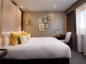 惠灵顿惠灵顿索菲特酒店的卧室配有一张带黄色枕头的大型白色床。