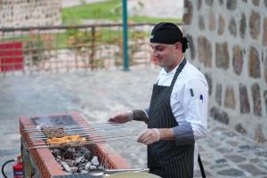 富查伊拉Dibba Mountain Park Resort的一个人在烧烤架上做饭