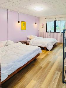 บ้านอัญชัน的配有粉红色墙壁和木地板的客房内的两张床