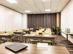 阿让Mercure Agen Centre的一间空的讲座室,配有桌椅