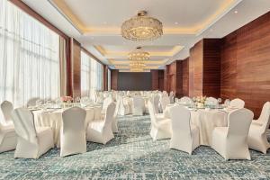武汉武汉汉口恒信希尔顿花园酒店的一间会议室,配有白色的桌椅和吊灯