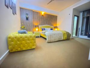 伊斯兰堡Viceroy Royal Hotel Apartment Islamabad的一间卧室配有一张床和两张黄色椅子