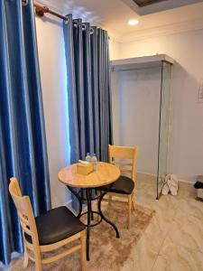 贡布Guesthouse Chamroeun Mongkul的一张桌子和椅子,房间带蓝色窗帘