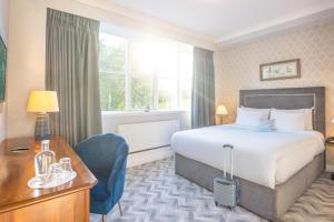 穆林加尔Bloomfield House Hotel, Leisure Club & Spa的配有一张床和一张书桌的酒店客房