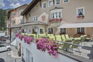 StrengenPosthotel Strengen am Arlberg的一座带椅子和鲜花的建筑的阳台