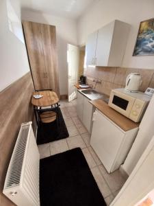 沙罗什保陶克Aquatherma Apartman的小厨房配有白色橱柜和微波炉