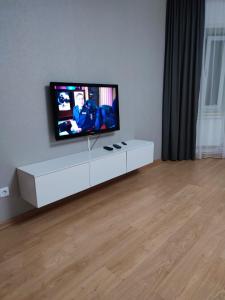 巴甫洛达尔Апартаменты Жаяу Мусы 7А的客厅配有白色橱柜上的平面电视
