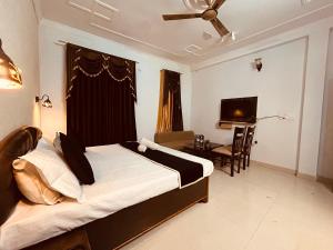 瑞诗凯诗Hotel 4 You - Top Rated and Most Awarded Property In Rishikesh的一间卧室配有一张床、一张书桌和一台电视