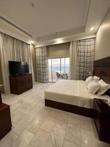 Al HumaizahVista Haql Hotel的一间卧室配有一张大床和一台电视。