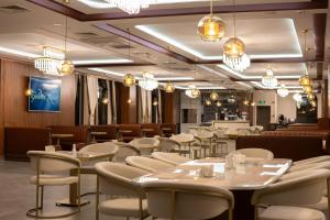 ArnavutköyGolden River Hotel By Continent的餐厅设有白色的桌椅和吊灯。