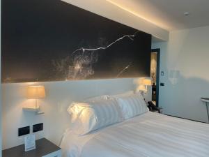 贝加莫Life Hotel的卧室配有白色床,墙上挂着一幅大画
